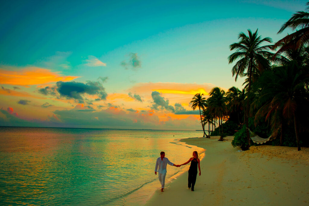Romantic Beach Walk: Couple at Sunset Among Palm Trees Wallpaper