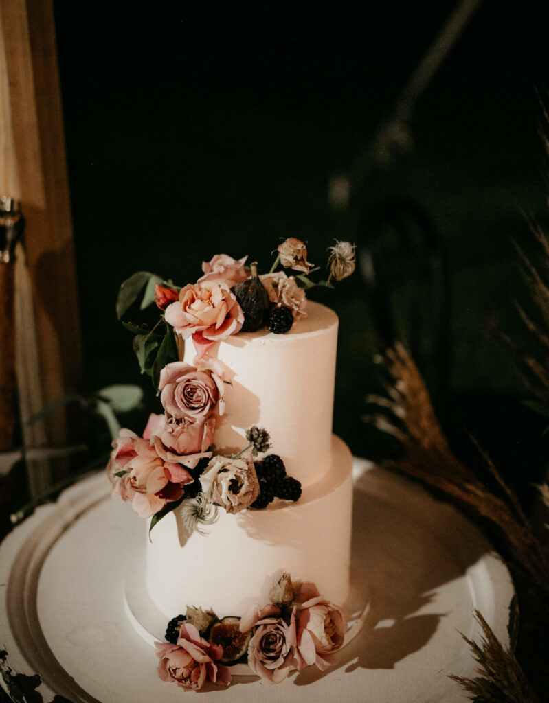 Two tier chiffon petal wedding cake with blush pink flowers in warm moody lighting wallpaper
