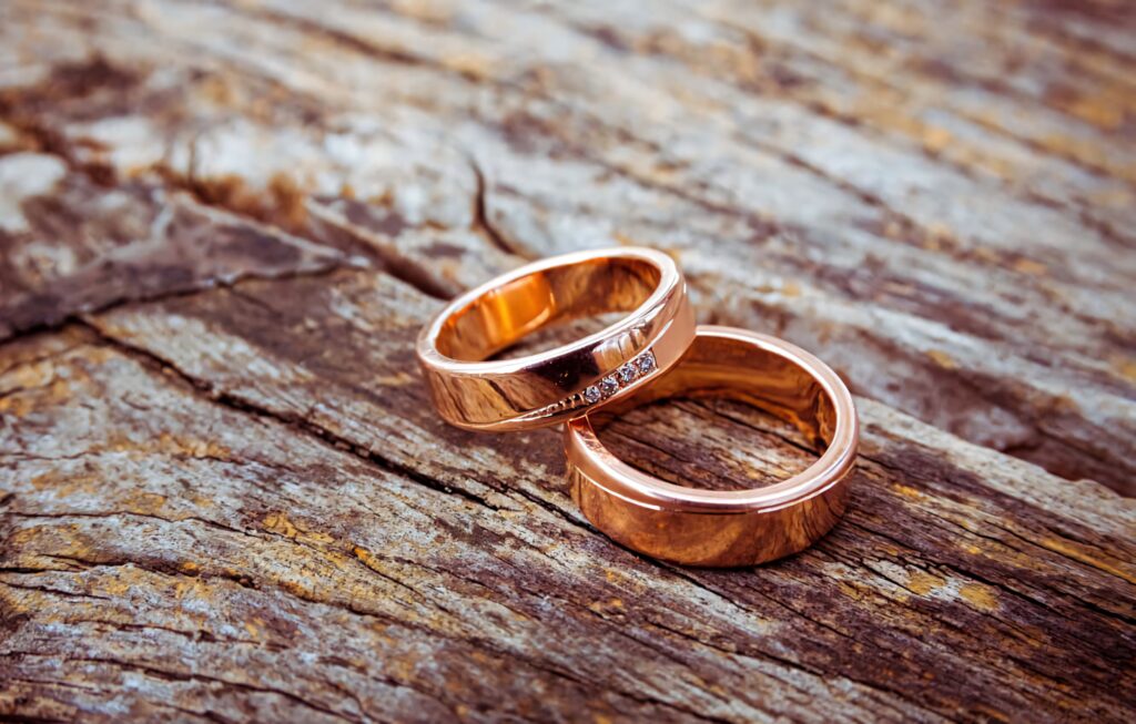 Rose gold couple engagement rings with diamonds on rustic textured wood background wallpaper