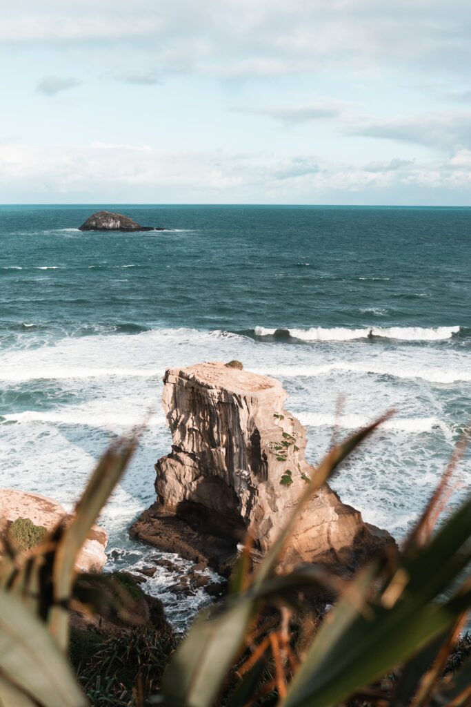 Rugged coastal rocks and deep blue sea under a cloudy sky serene ocean wallpaper background
