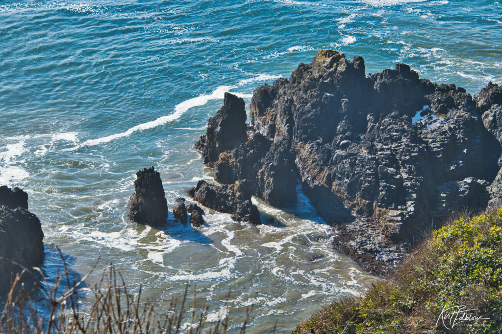 Rugged coastal rocks with vibrant blue sea waves washing ashore in high resolution wallpaper