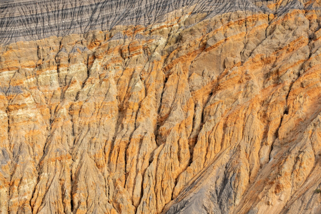 Rugged crater surface with orange brown gray textures natural erosion geological wallpaper
