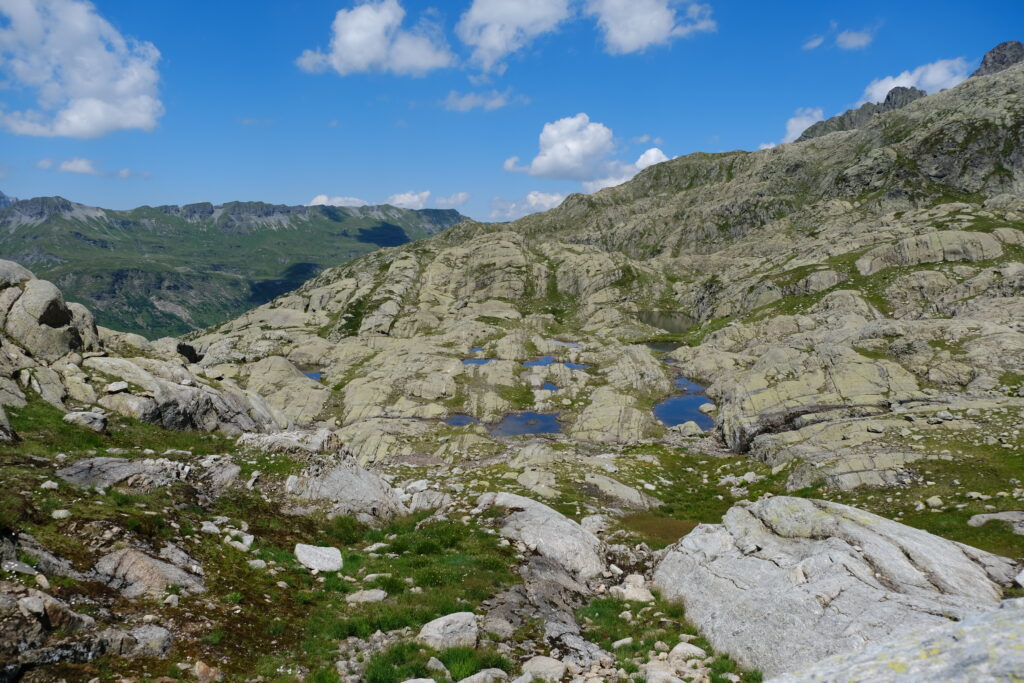 Rugged mountain landscape with stone formations and pools under vibrant blue cloudy sky wallpaper