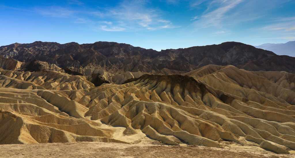 Rugged mountain peaks with textured rocky surfaces under clear blue sky natural landscape wallpaper