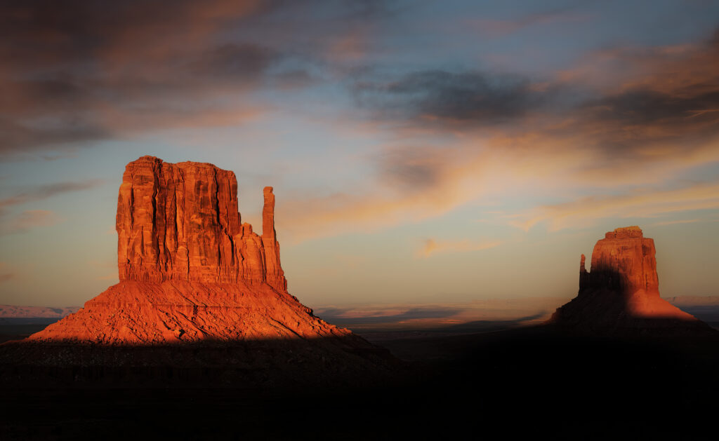 Rugged mountain rocks in warm sunlight with dramatic shadows under dynamic cloudy sky wallpaper