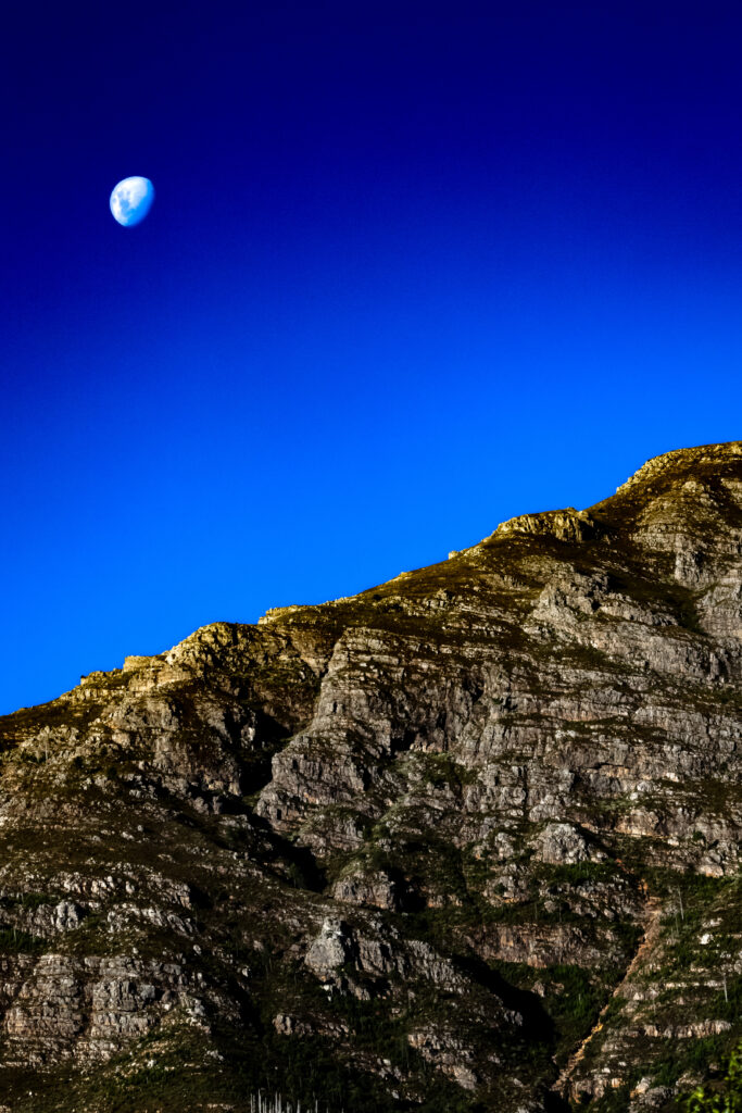 Rugged mountain slope under deep blue sky with vivid half moon natural landscape wallpaper