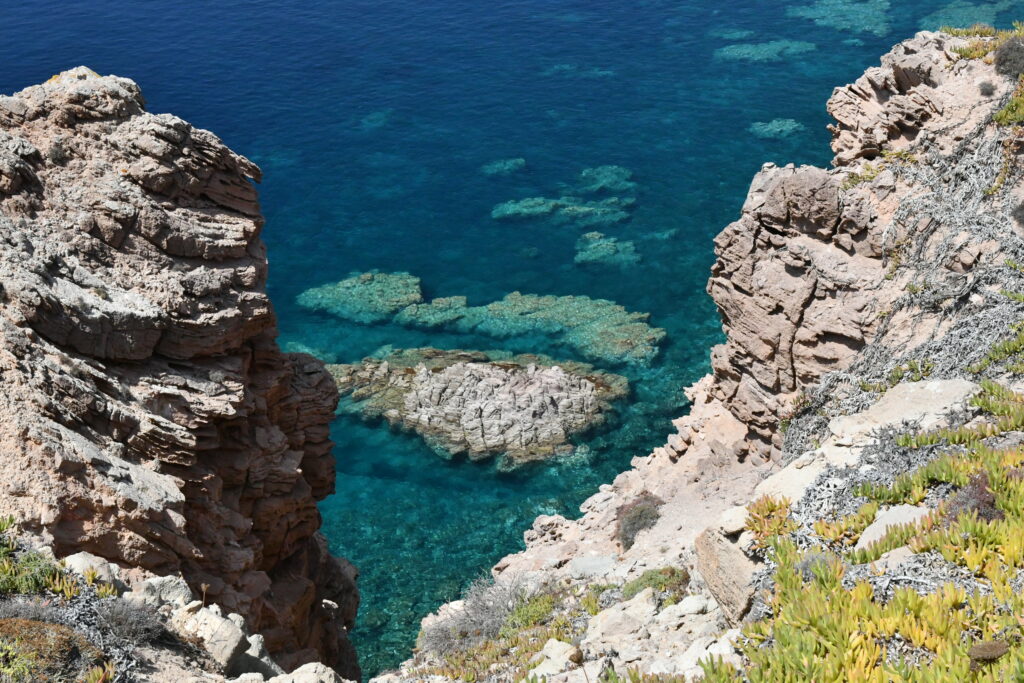 Rugged rocky cliffs framing clear turquoise waters with vibrant reefs and marine life wallpaper