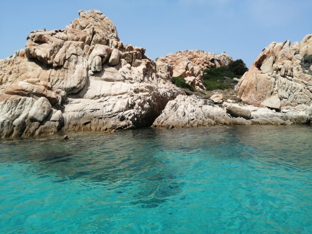Rugged rocky cliffs above clear turquoise sea under bright blue sky natural coastal landscape wallpaper