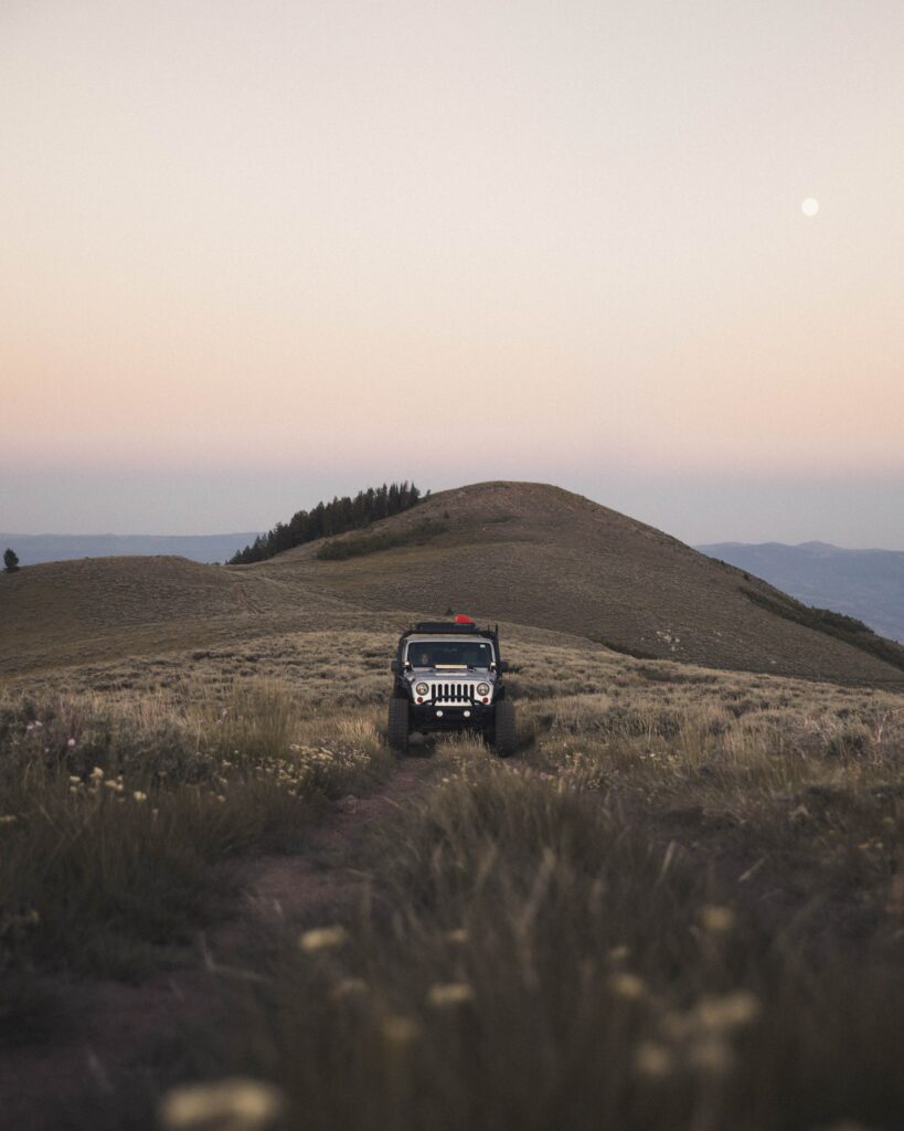 Off-Road Adventure: Rugged SUV in Grassy Terrain with Mountain View Wallpaper