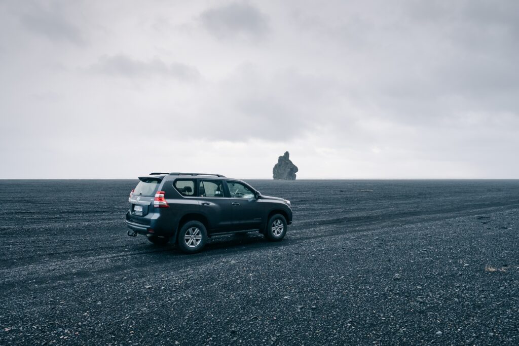 Rugged SUV on Rocky Terrain Under Dramatic Cloudy Sky Wallpaper