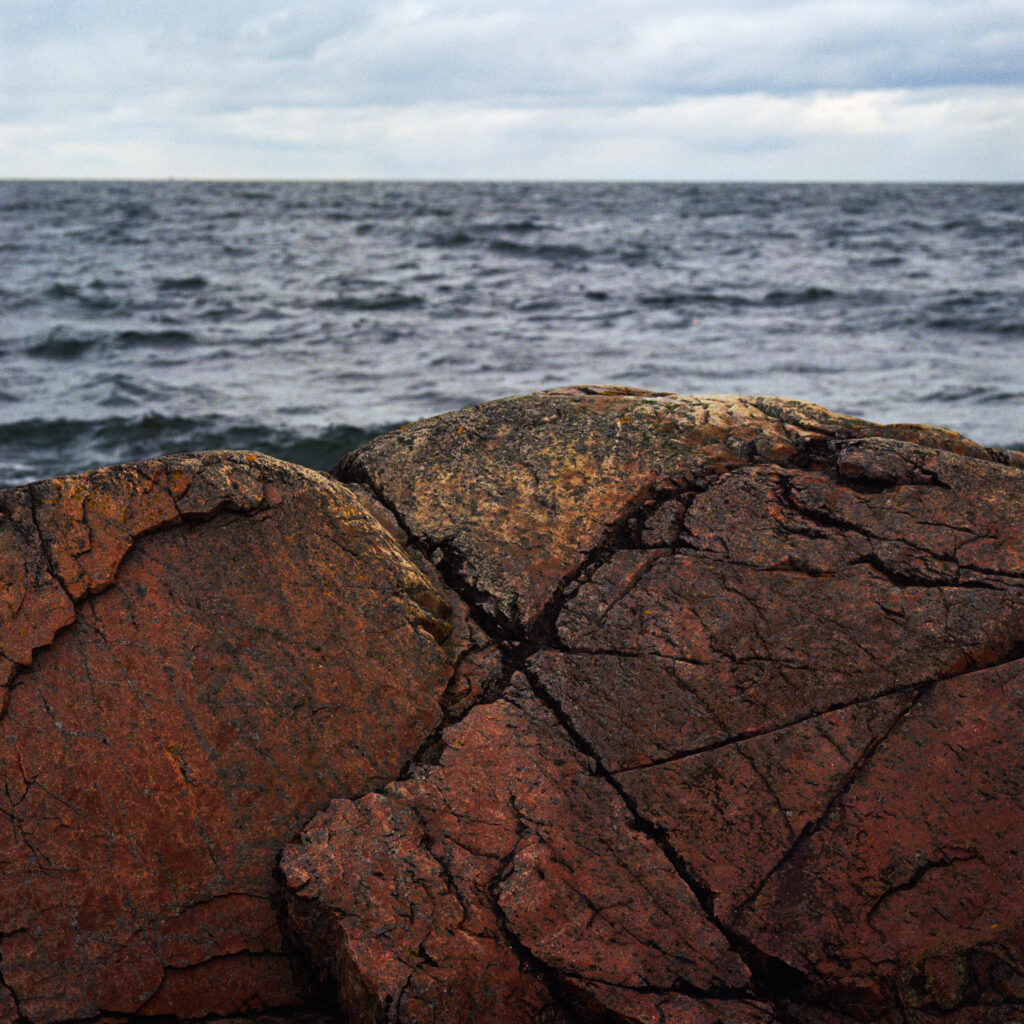 Rugged rocky seascape with textured stones foreground dark rippling sea and cloudy sky wallpaper