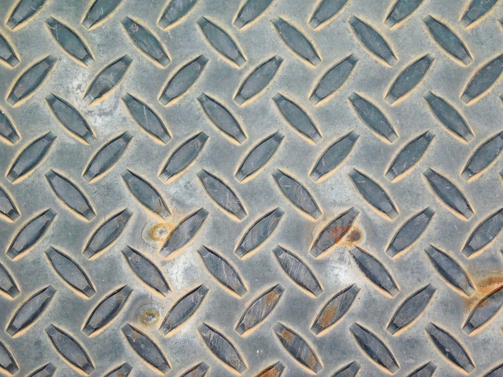 Rugged steel diamond plate wallpaper with raised tread and weathered grey rust texture background