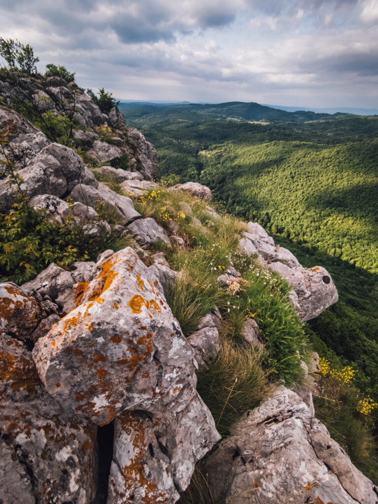 Rugged stone formations with rolling green hills under a partly cloudy sky natural landscape wallpaper