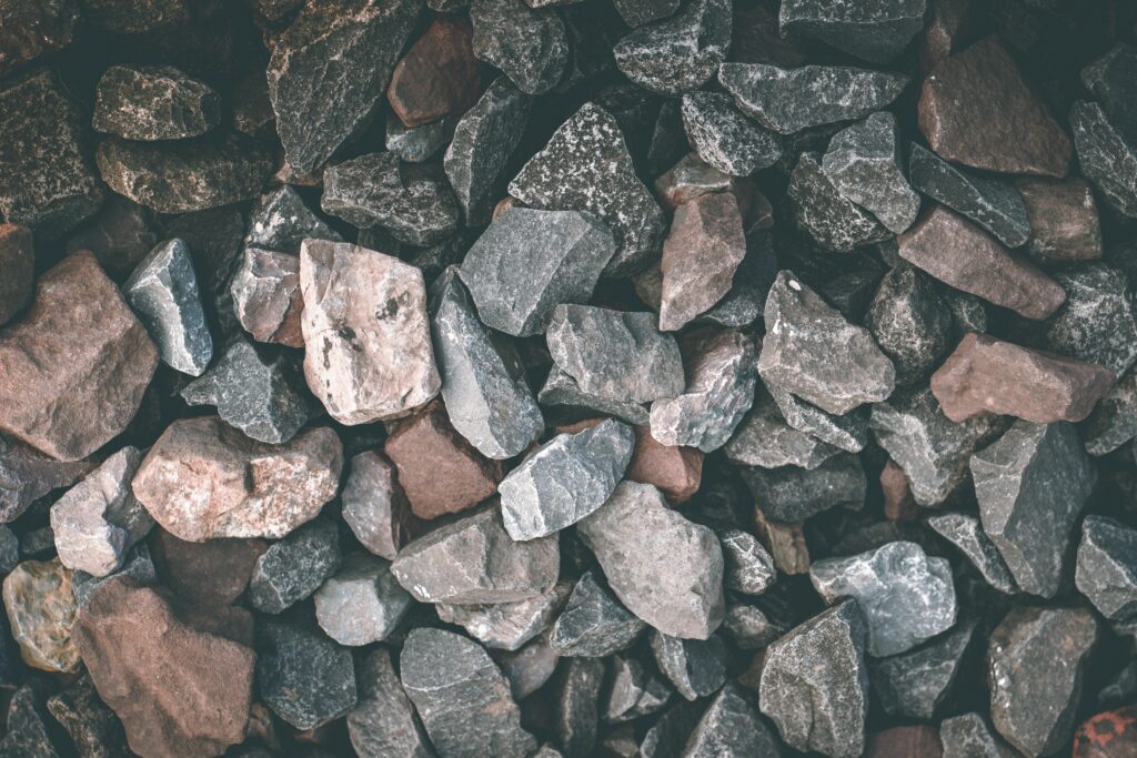 Close-up of rugged natural stones and pebbles in earthy gray brown and muted blue tones wallpaper