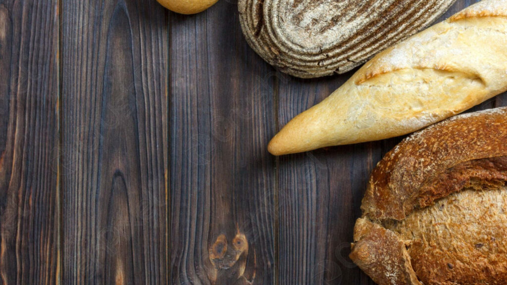 Rustic artisan breads with golden crusts on dark wooden table bakery food background wallpaper