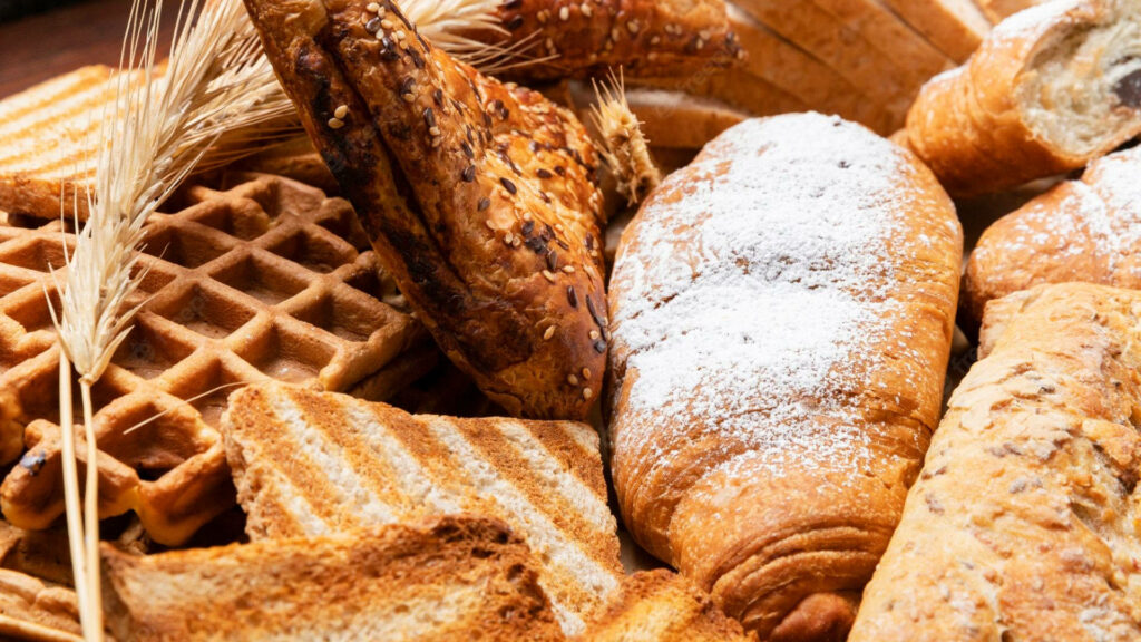 Assorted fresh breads golden waffles crispy toast rustic bakery wallpaper warm kitchen background