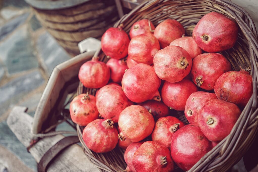 Rustic Basket of Vibrant Pomegranates - Charming Wallpaper Background