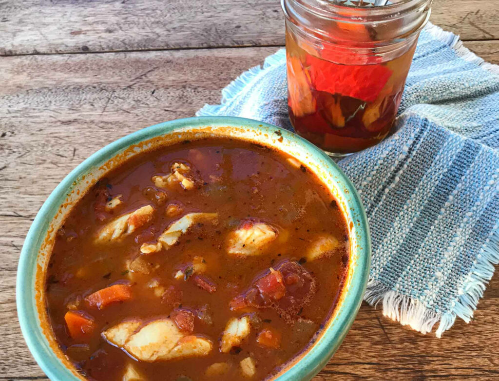 Rustic Bermuda Fish Chowder with tender fish and vegetables on wooden table with spicy peppers Wallpaper