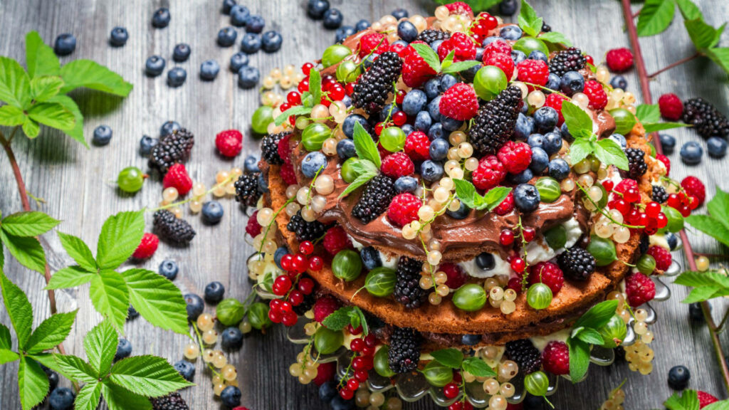 Rustic cake with mixed berries and fresh green leaves vibrant dessert wallpaper background