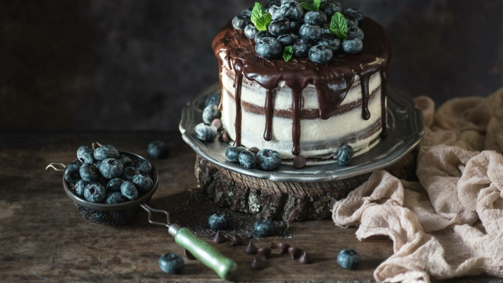 Rustic cake with fresh blueberries and chocolate ganache on wooden surface dessert scene wallpaper