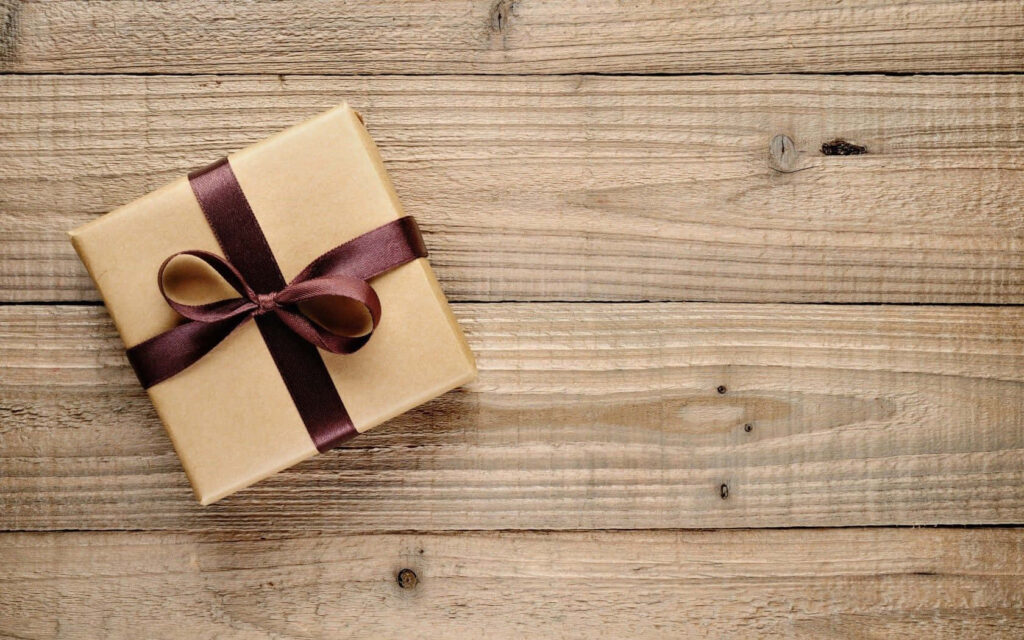 Neutral brown paper gift box tied with dark ribbon on rustic wooden background wallpaper