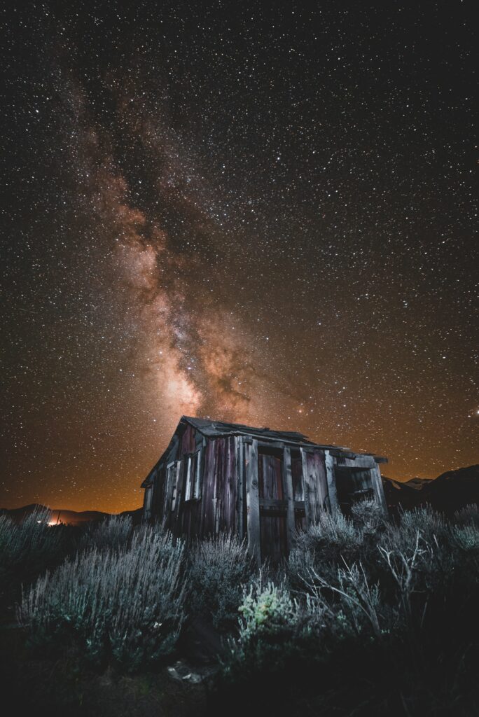 Rustic old building under vibrant starry sky and glowing Milky Way near June Lake USA at night Wallpaper