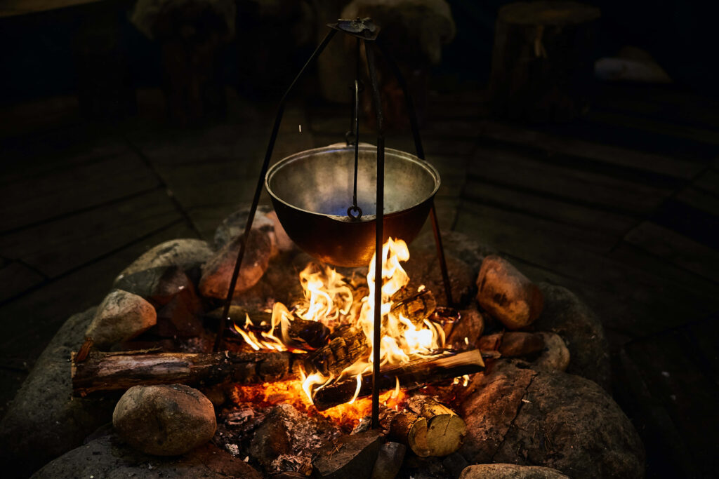 Rustic campfire with metal pot over flames in stone firepit cozy outdoor cooking scene wallpaper