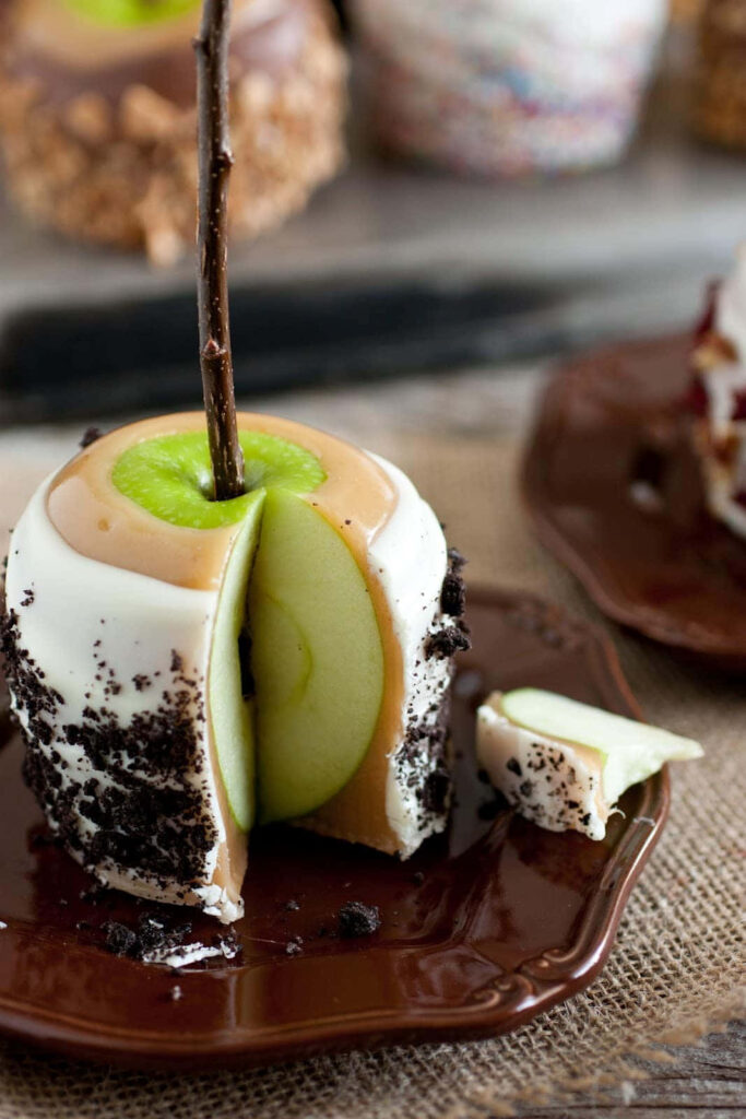 Close-up of sliced green caramel apple with white chocolate and cookie crumbs on rustic background Wallpaper