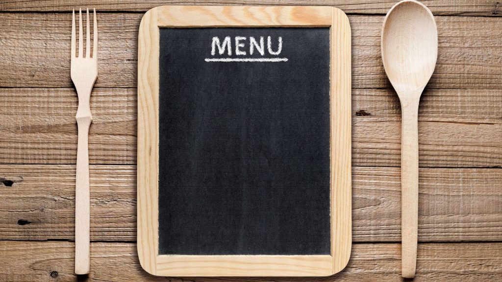Rustic wooden background with empty black chalkboard menu and wooden fork and spoon flat lay Wallpaper