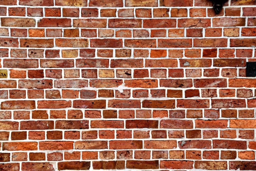 Rusty brown and terracotta brick wall wallpaper with white mortar and weathered industrial texture