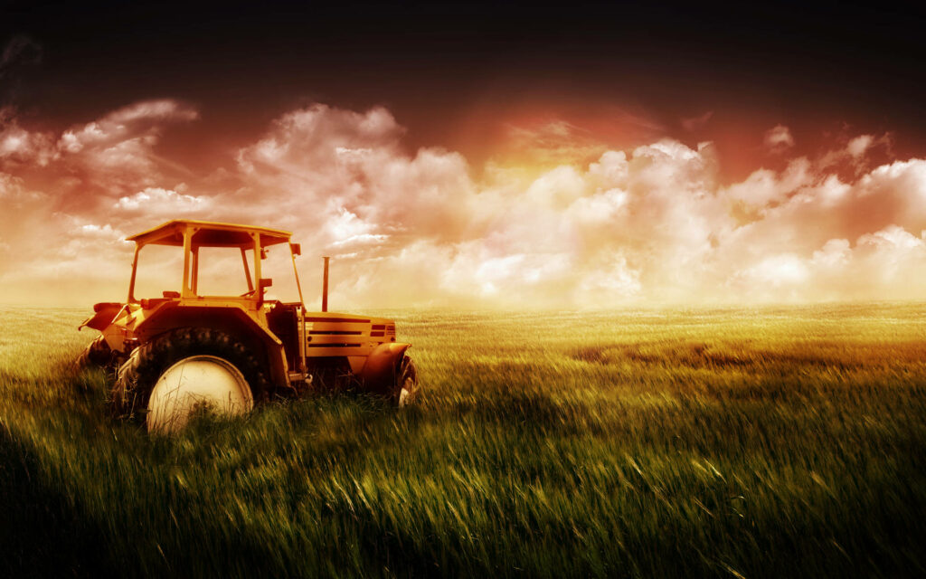 Vintage yellow tractor in lush field at dramatic glowing sunset rustic farmland wallpaper