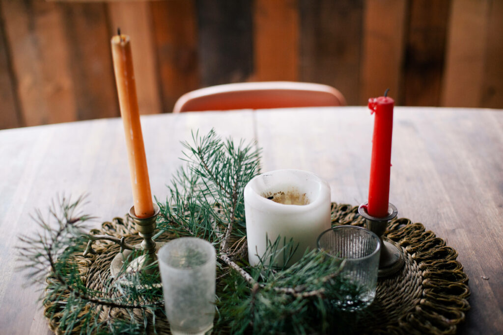Rustic Christmas Table Setting with Candle Centerpiece & Pine Branches Wallpaper