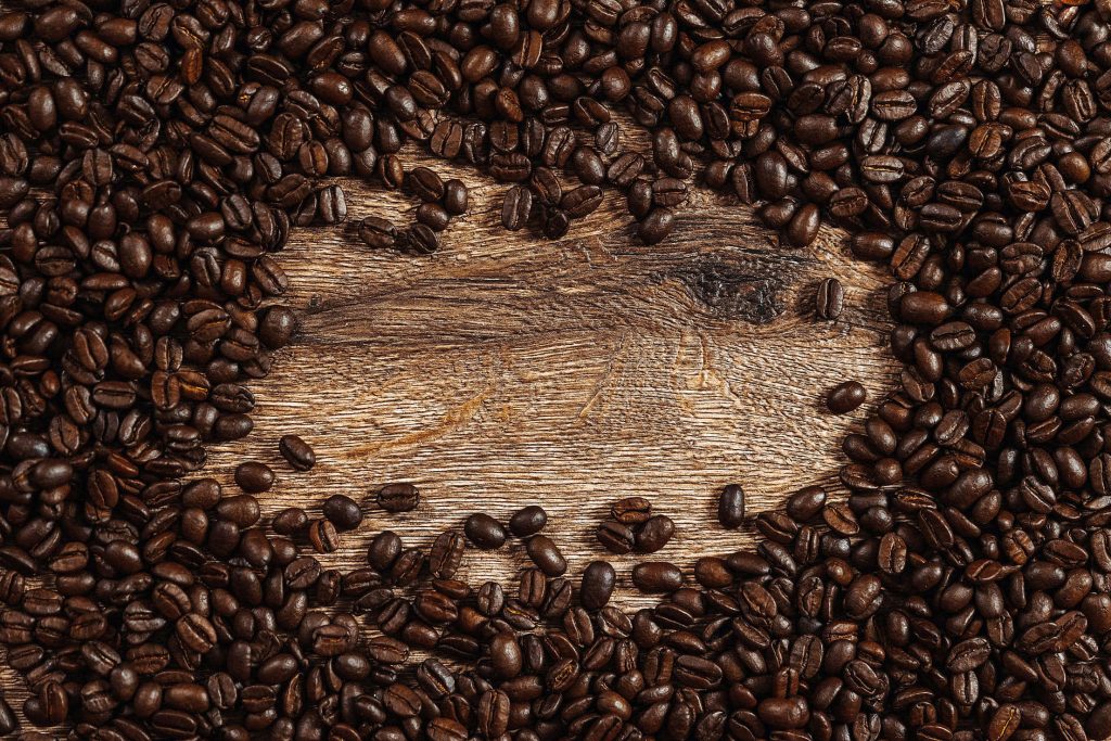 Top-down rustic coffee beans border on weathered wood background warm inviting wallpaper
