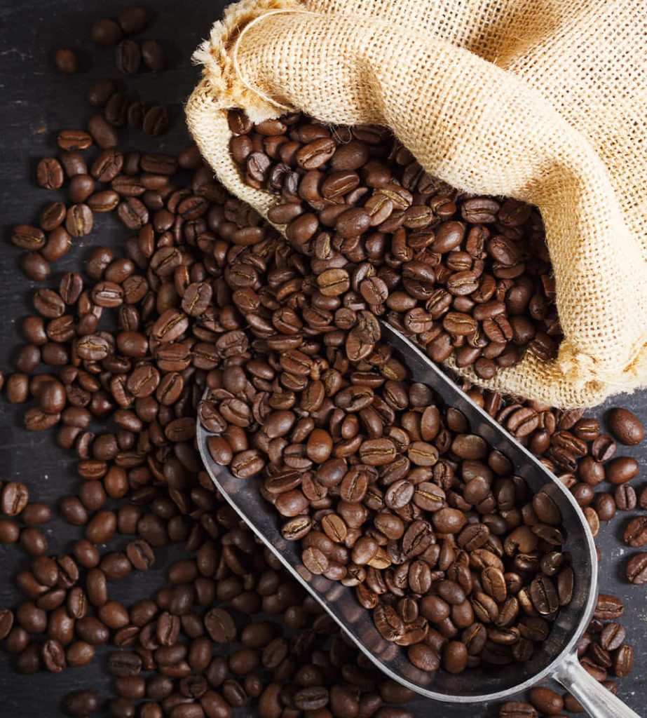 Rustic coffee wallpaper with fresh dark roasted beans spilling from burlap sack and scoop