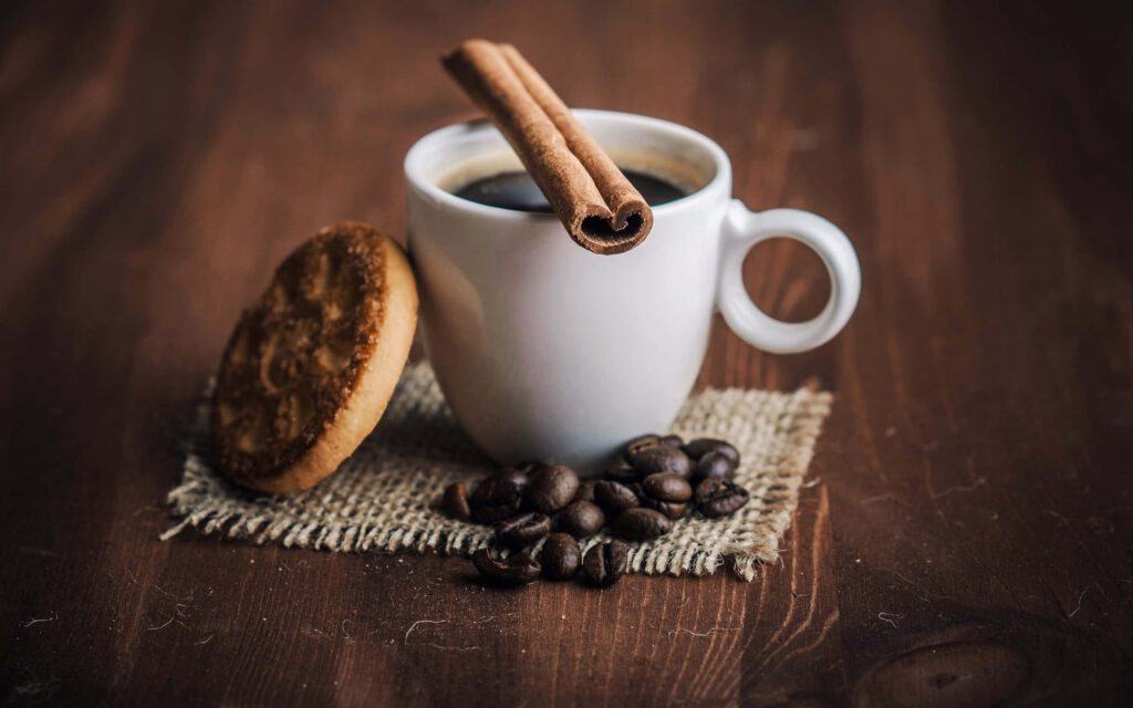 White cup of black coffee with cinnamon stick roasted beans cookie on burlap wooden background Wallpaper