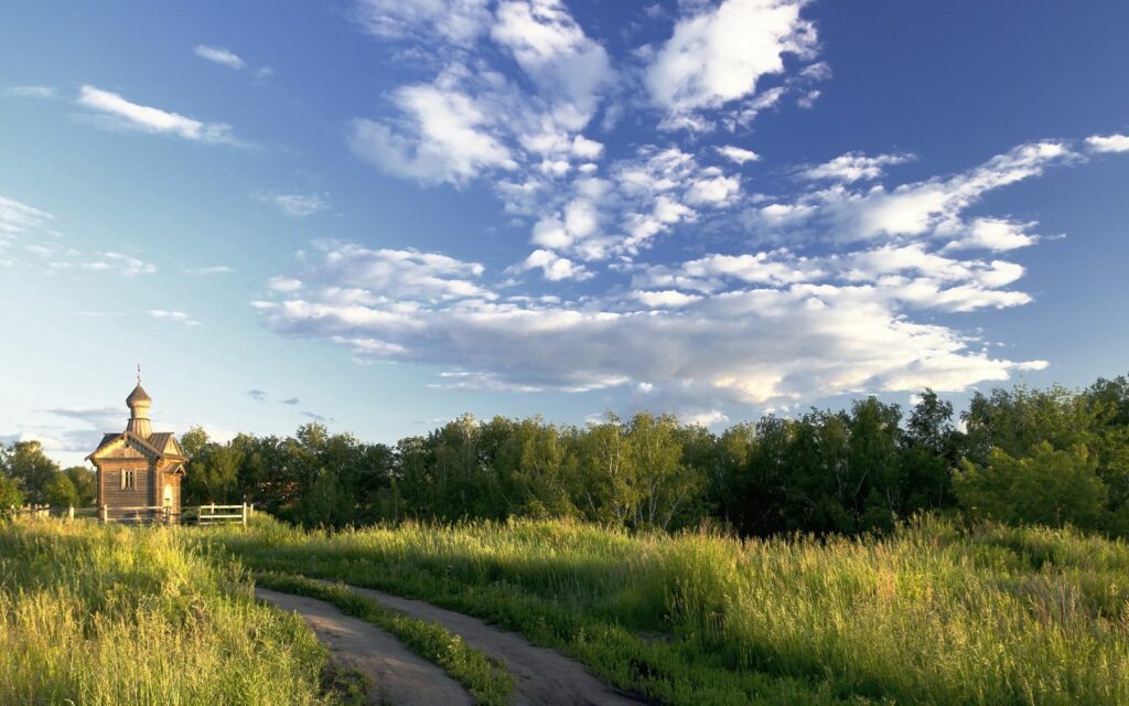 Rustic country temple by winding dirt road golden fields green trees vibrant blue sky wallpaper