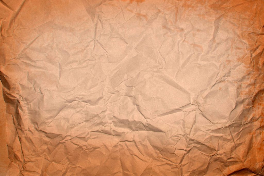 Warm orange crumpled paper wallpaper with rustic folds and vintage textured background design