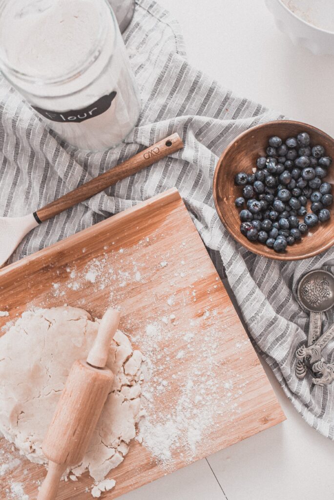 Rustic Baking Scene: Dough, Blueberries, and Vintage Utensils Wallpaper