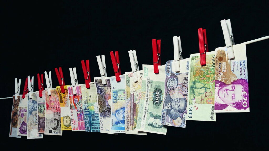 Financial Ties: A Captivating Display of Clipped Currency Notes with a Dark Money Background Wallpaper