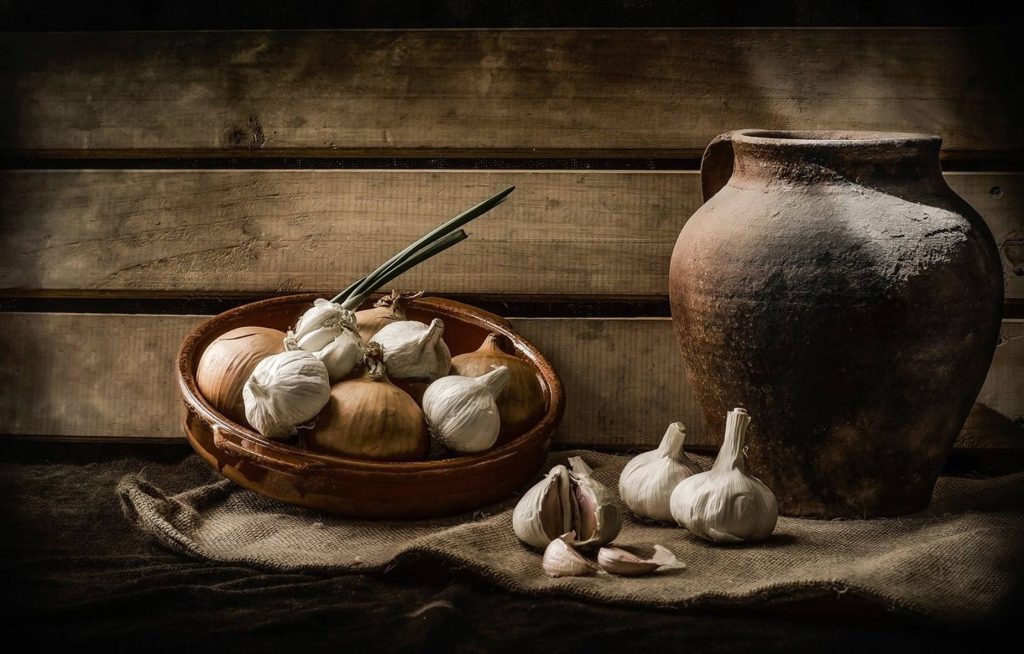 Rustic still-life of garlic onions in clay bowl with pottery jug on wood and burlap backdrop Wallpaper