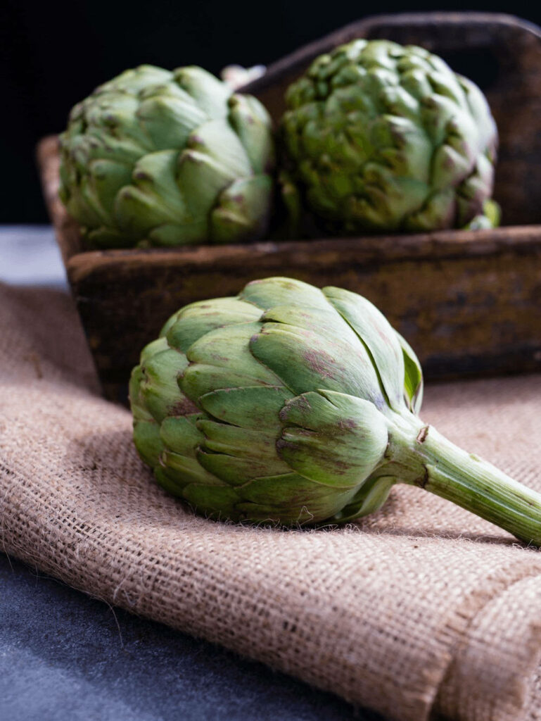 Fresh green artichokes on burlap with rustic wooden box natural kitchen wallpaper background