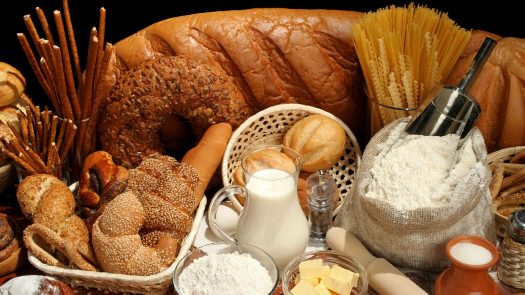 Rustic still life with fresh breads sesame bagels milk flour pasta butter baking ingredients background Wallpaper