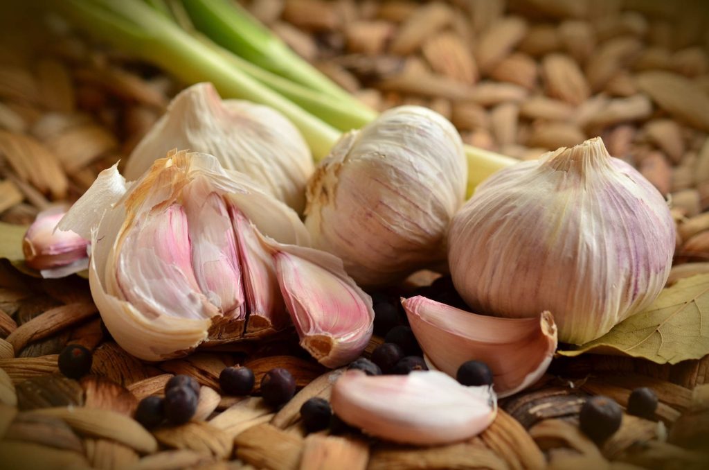 Rustic culinary wallpaper with fresh garlic cloves herbs and peppercorns on wicker texture