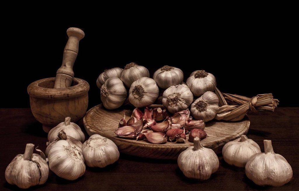 Rustic garlic bulbs cloves with wooden mortar pestle moody kitchen still life wallpaper background