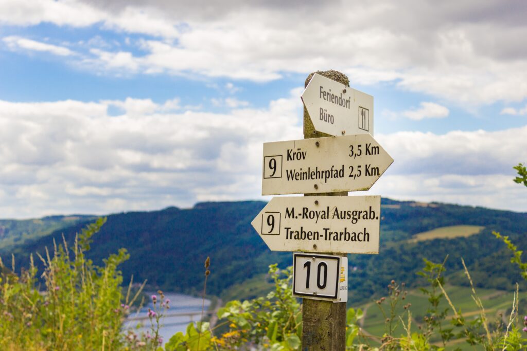 Rustic German signpost with mountain view lush green hills and cloudy skies scenic landscape wallpaper