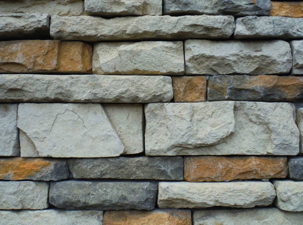 Realistic gray and brown stacked stone wall wallpaper with rustic masonry texture background