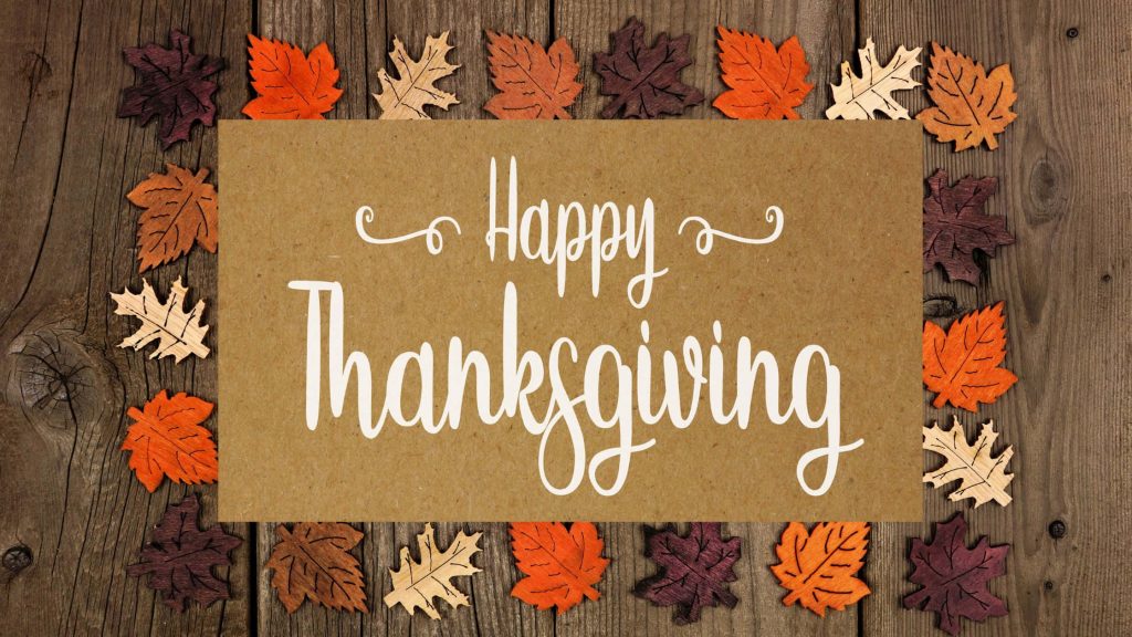 Rustic Thanksgiving wallpaper with Happy Thanksgiving sign and vibrant autumn leaves on wood
