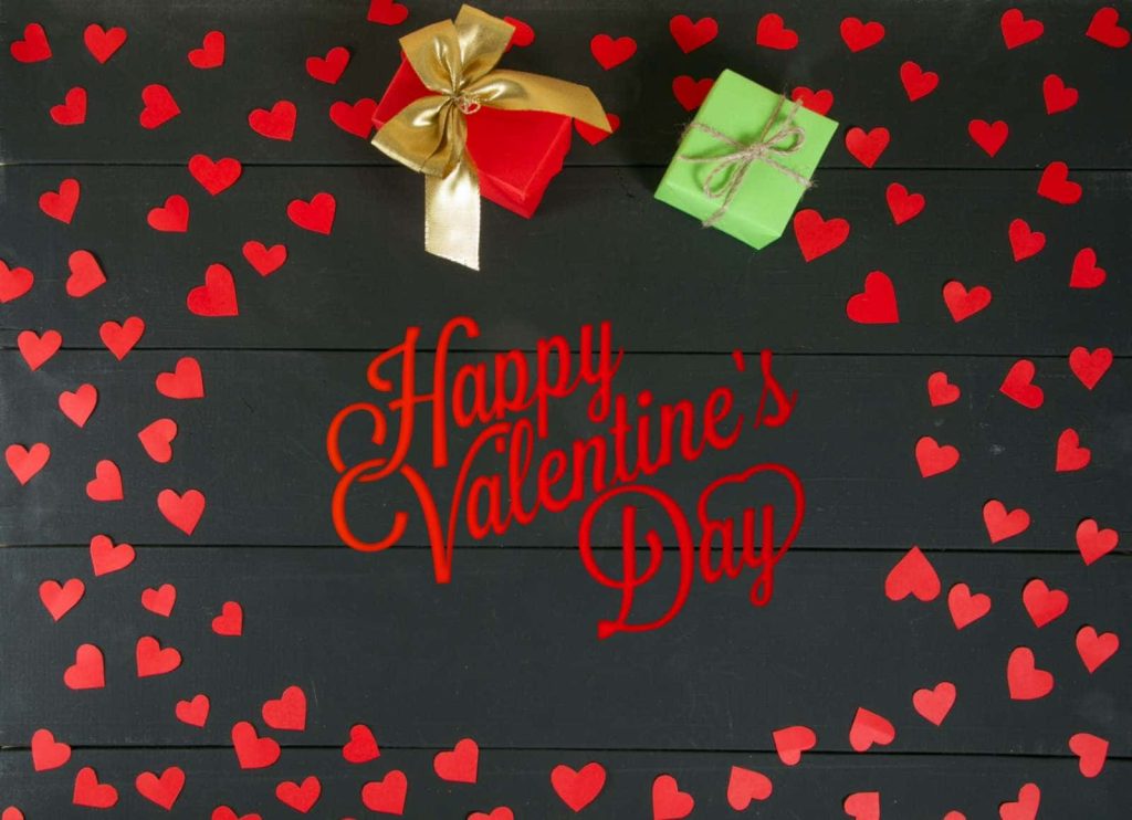 Happy Valentines Day flat lay with red hearts and festive gift boxes on rustic black wood Wallpaper