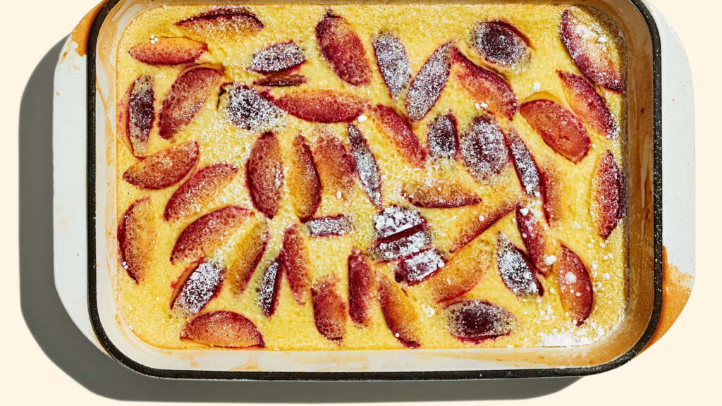 Rustic Italian prune plum cake with powdered sugar and vibrant red plum slices in sunlight Wallpaper