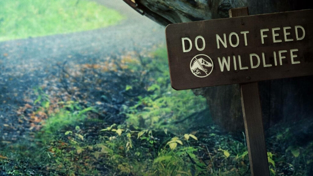 Rustic woodland path with weathered Do Not Feed Wildlife sign Jurassic World Dominion Big Rock Wallpaper